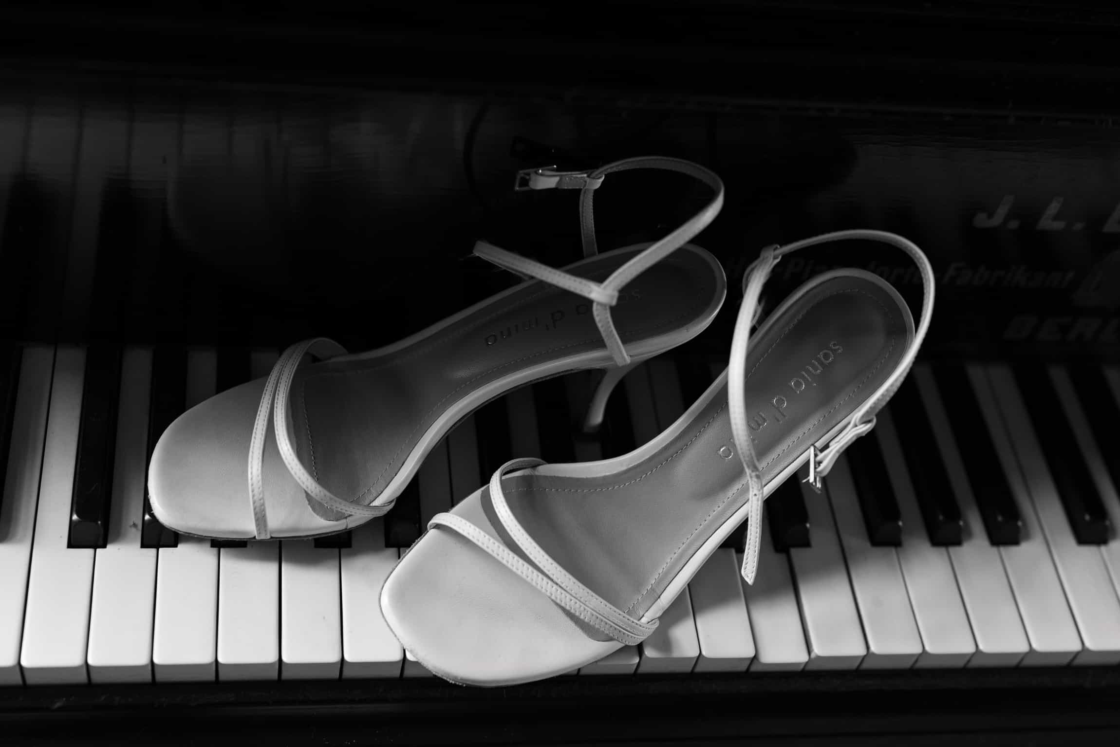 Weiße Brautschuhe auf schwarz-weißen Klaviertasten, minimalistische Komposition