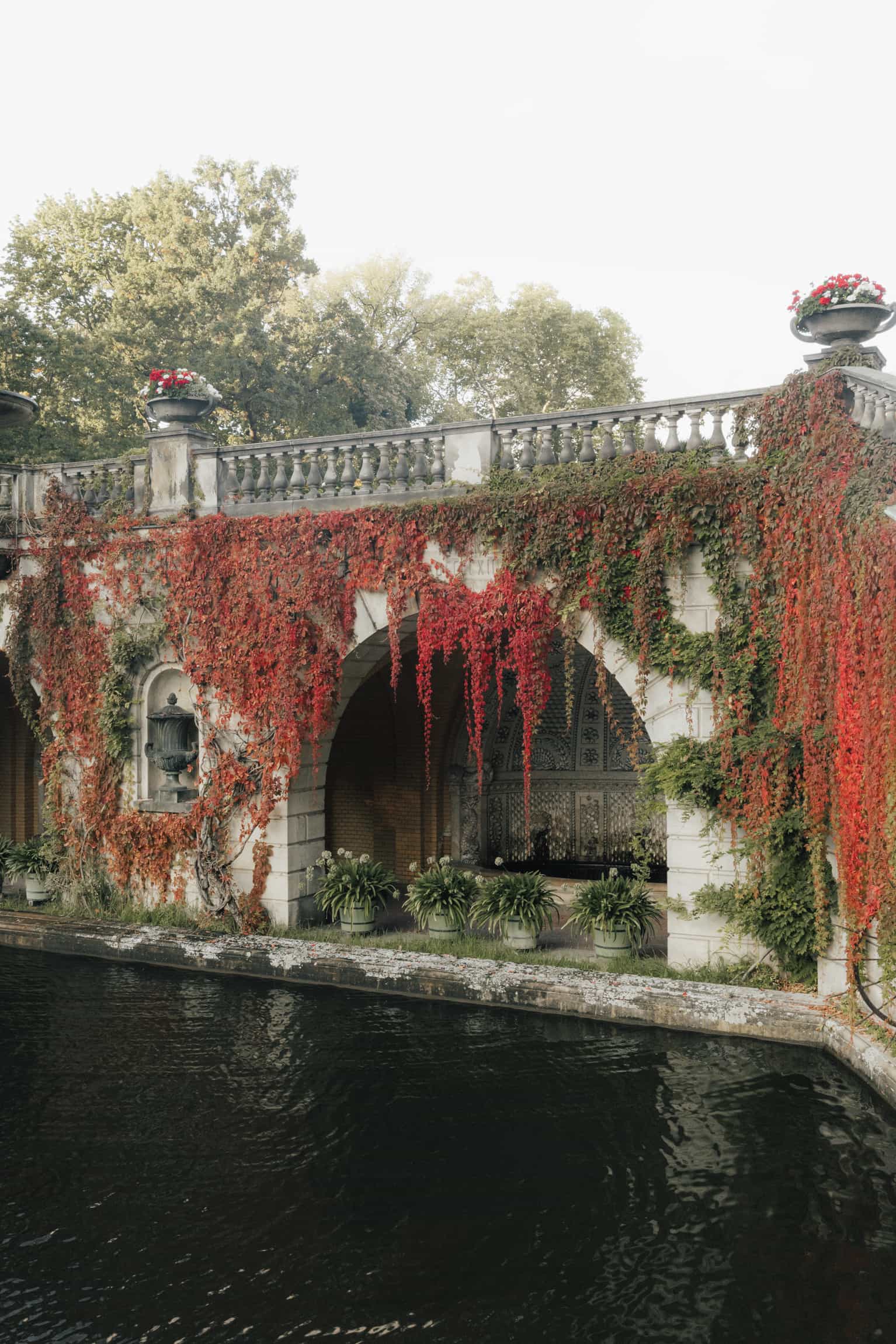 Von rotem Efeu bedecktes klassisches Gebäude mit Balustrade über Wasser