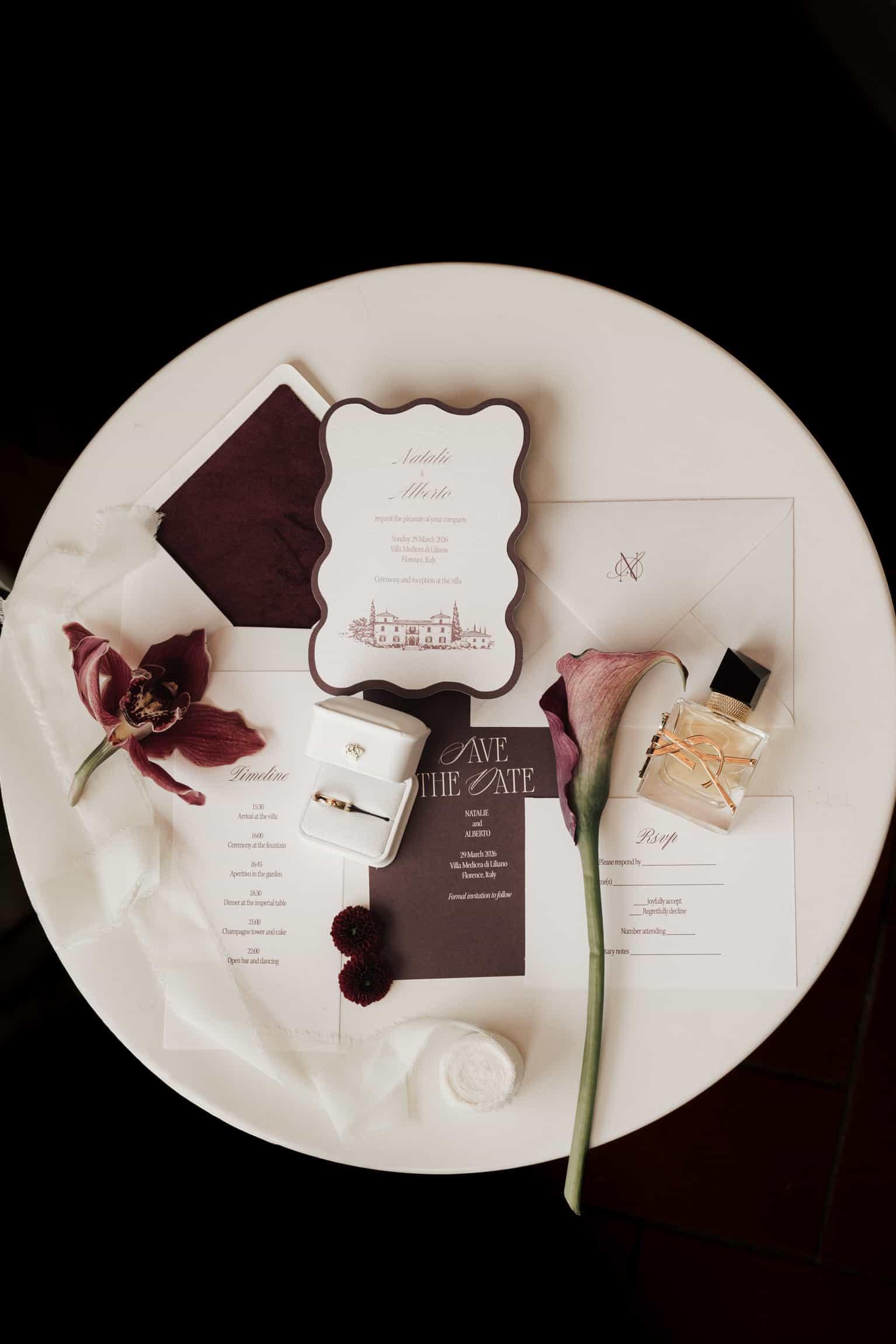 Hochzeitspapeterie mit burgunderroten Blüten und Details auf einem weißen Untergrund von oben