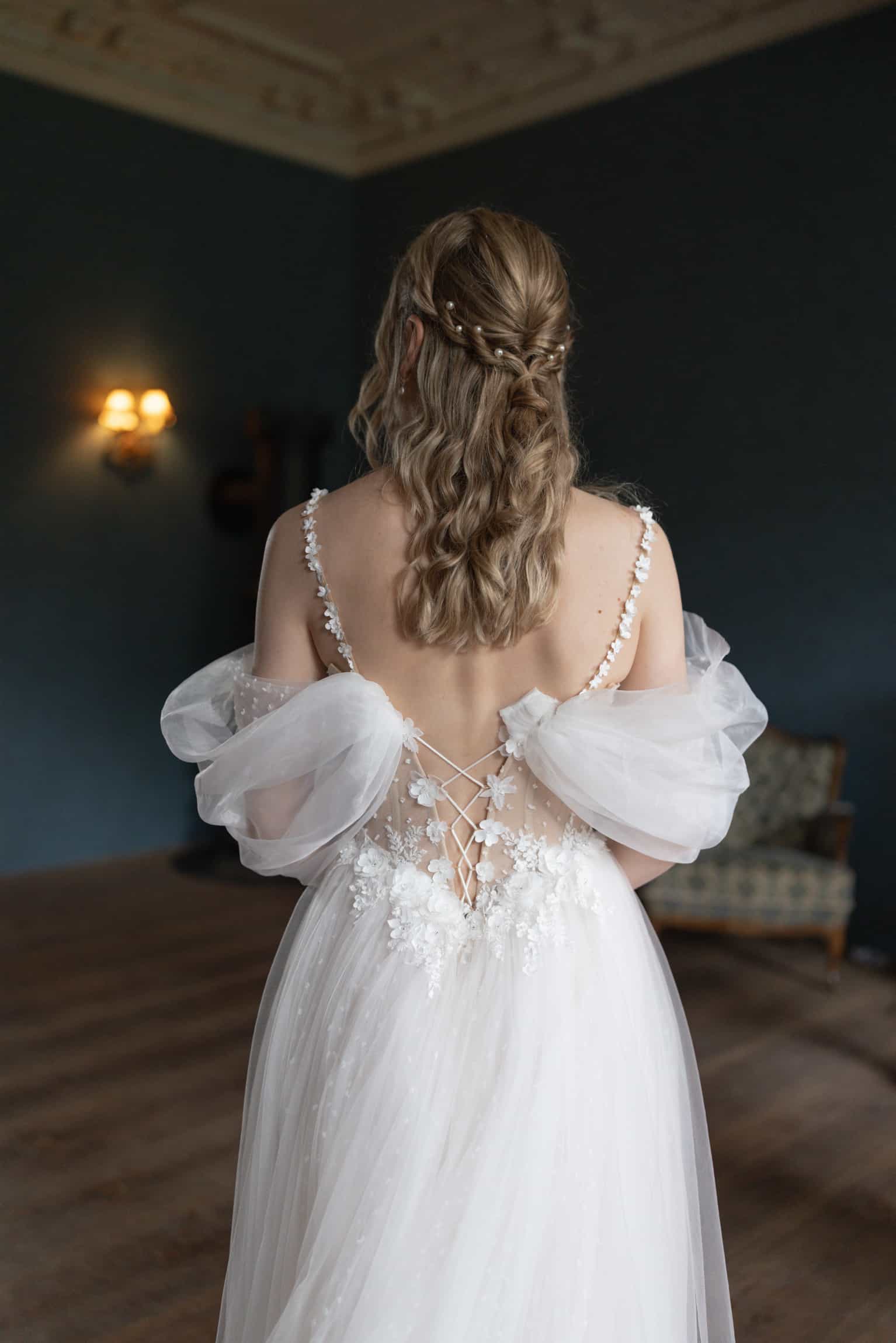 Bride from behind in an off-shoulder tulle gown with beaded corset and braided hair