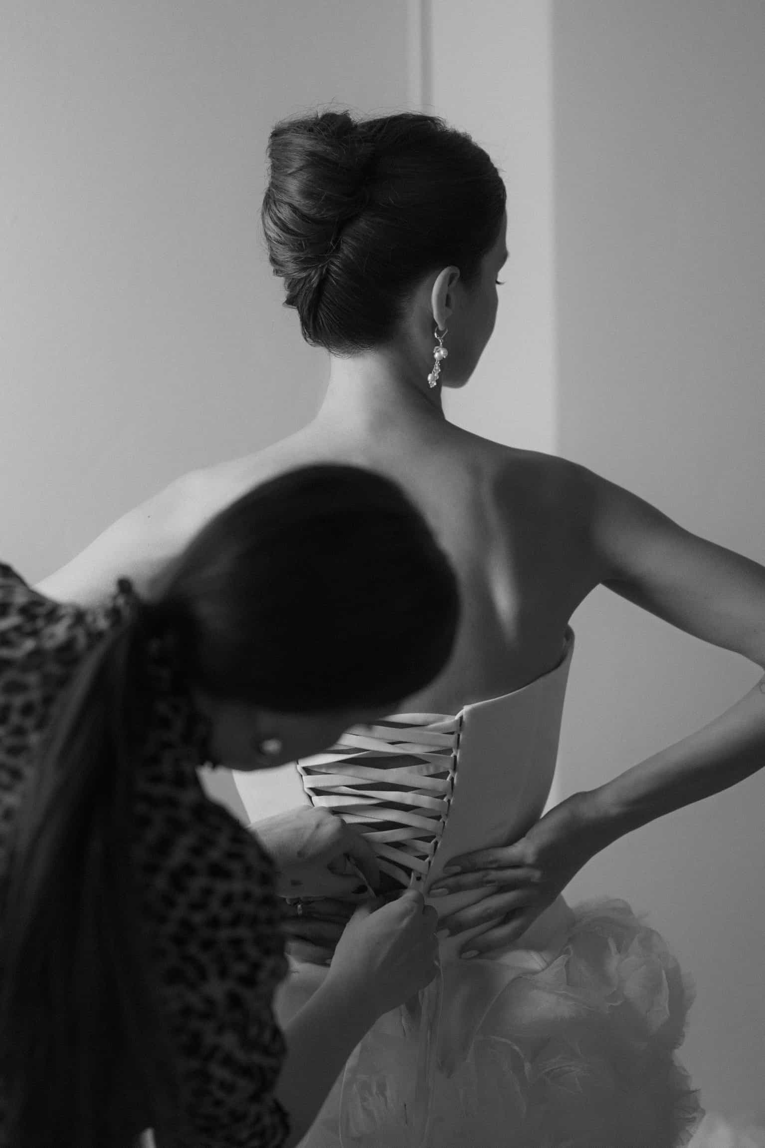 Back view of bride in an elegant lace-up wedding dress showing intricate corset detail and updo