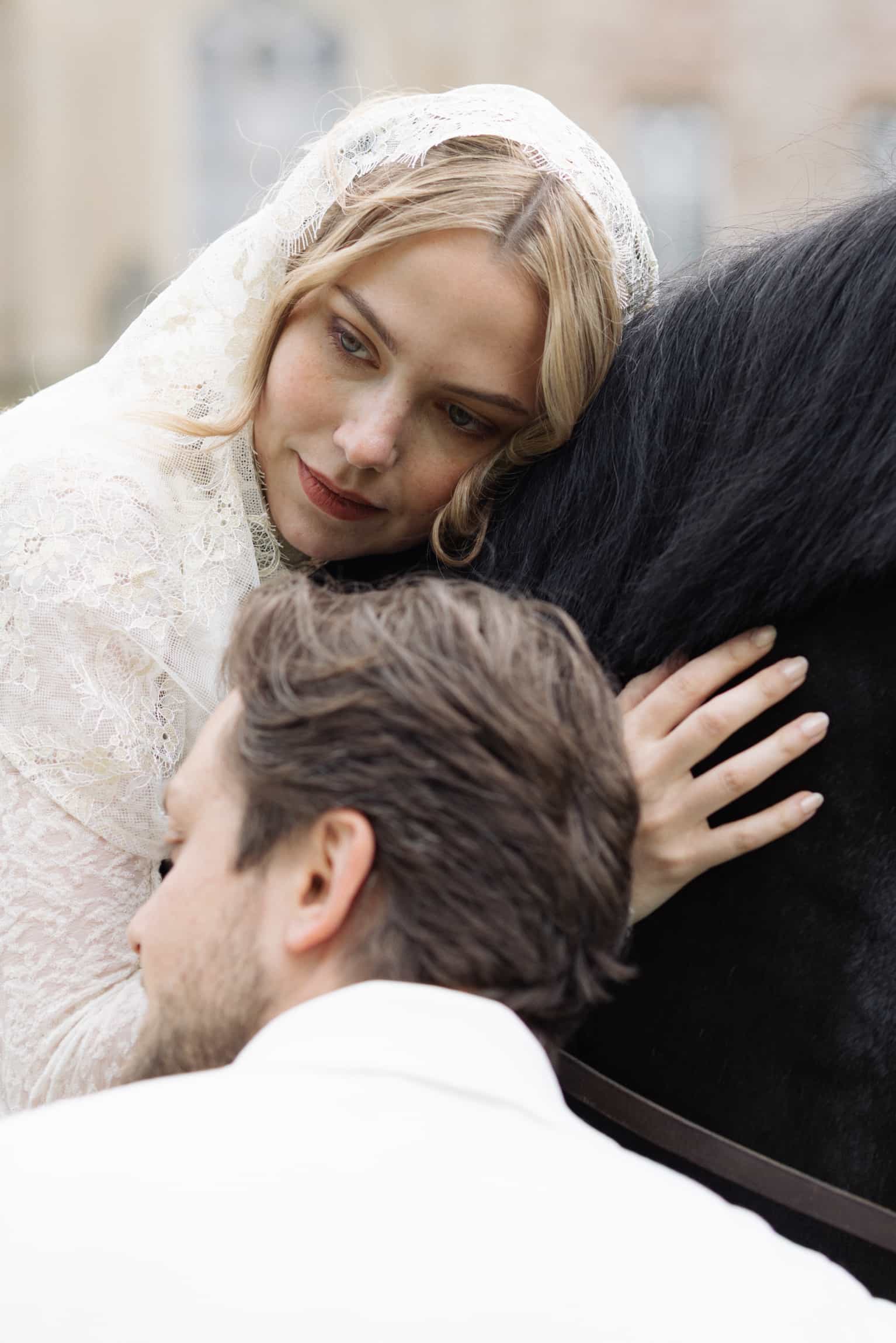 Bride in a delicate lace veil leaning toward groom in an intimate close black-and-white portrait