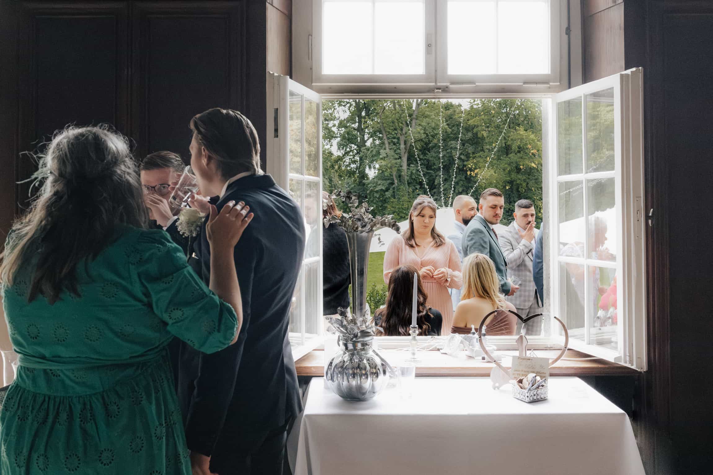 Interior view through open classical doors revealing a garden ceremony with guests and white tablecloths