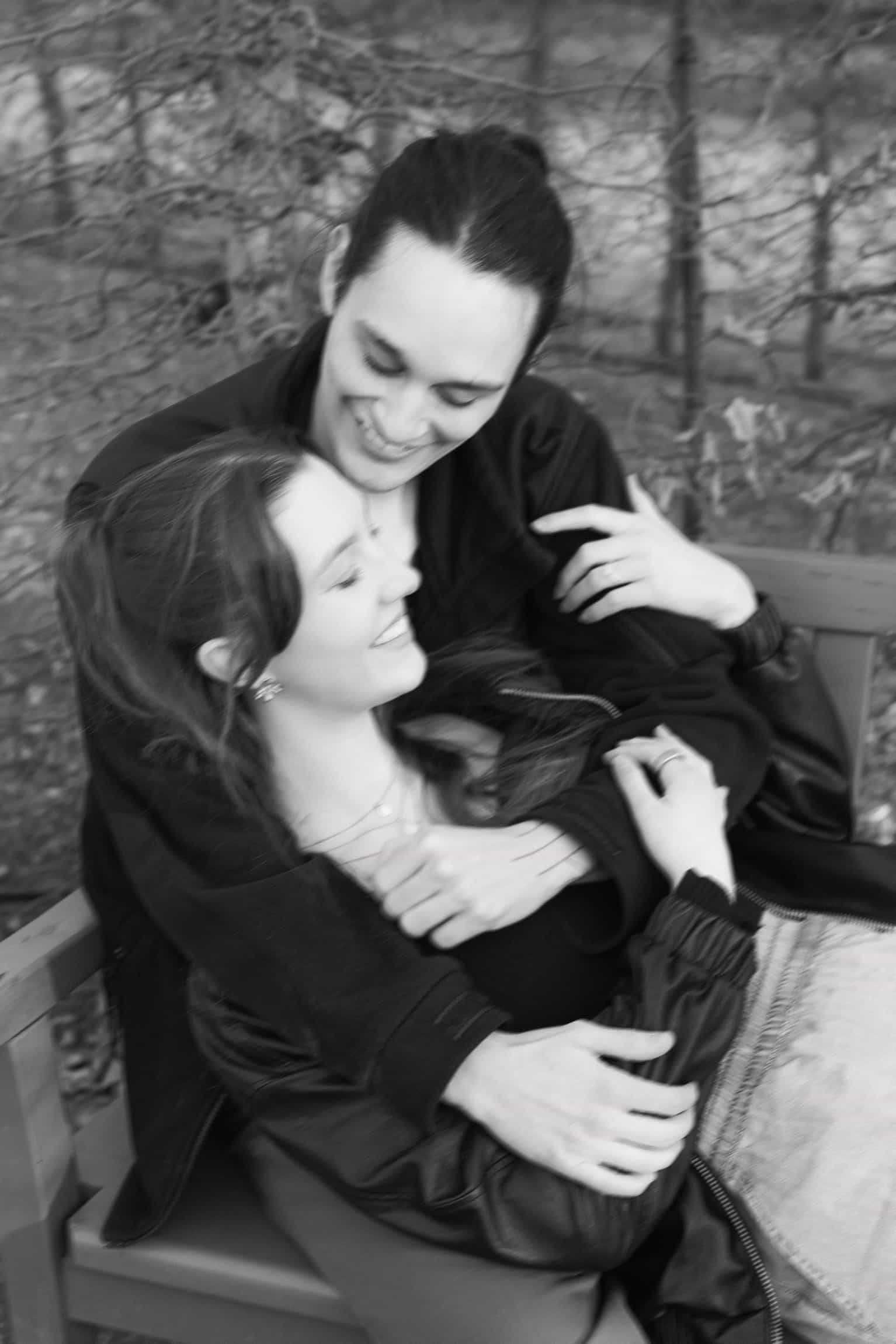 Bride and groom embracing in black and white among bare winter trees in a natural outdoor setting