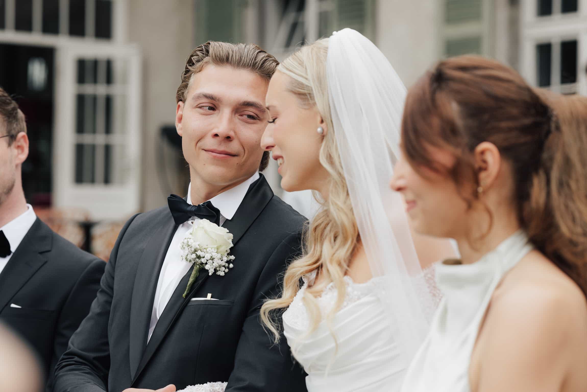 Groom's authentic reaction and eye contact during the wedding ceremony with guests blurred behind