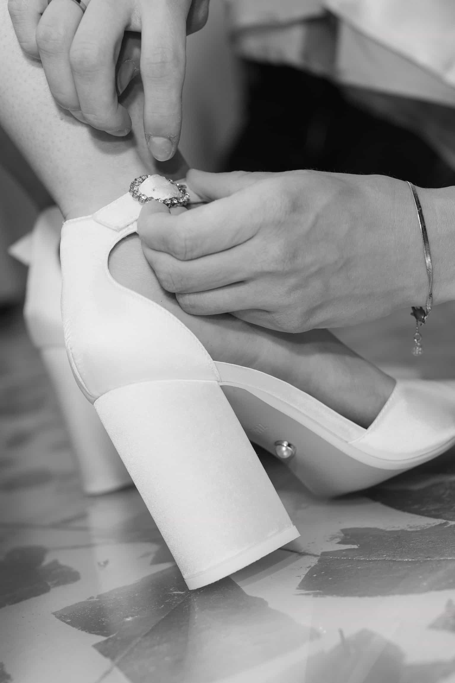 Close-up of bride and groom's hands exchanging wedding rings, white dress fabric visible