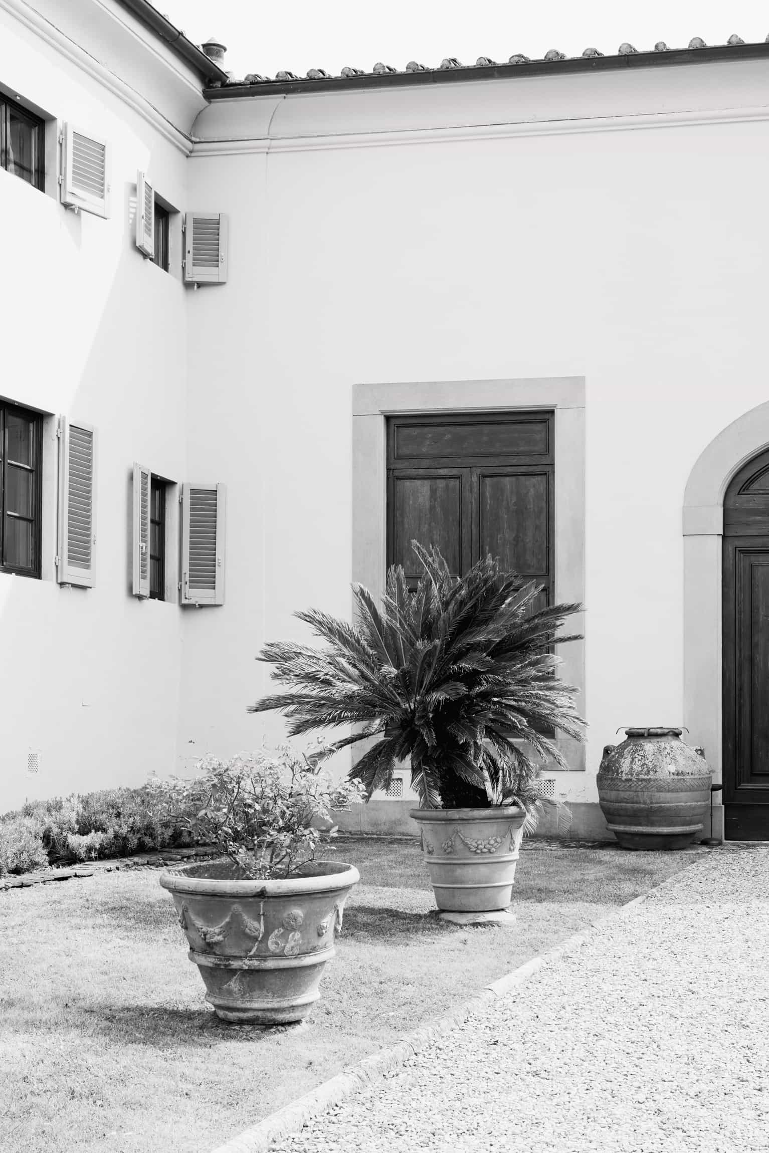 Serene white-walled courtyard with potted plants and an arched doorway, wedding venue in black and white