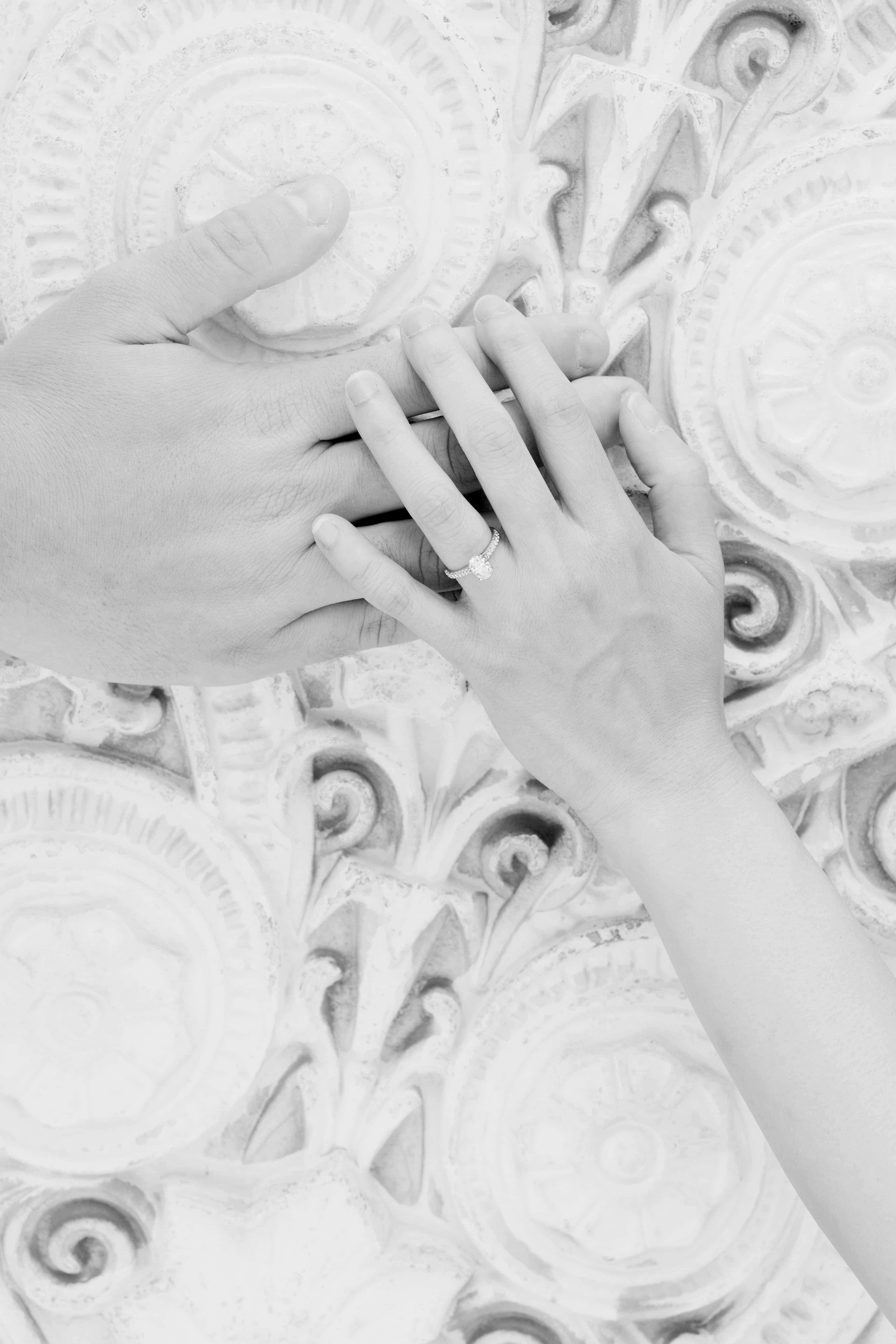 Bride and groom's hands with wedding rings resting on a white ornamental architectural detail