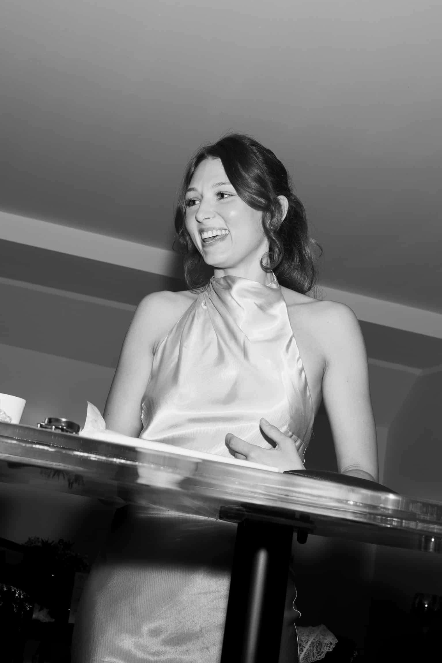 Black-and-white portrait of a woman sitting at a grand piano, smiling, with side natural light